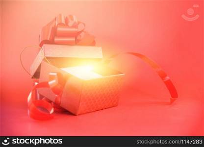 Open Gift Box rays light on red background / red present box with red ribbon bow for Merry Christmas Holiday Happy new year or Valentines day on red background - Surprise Gift Box