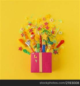 open gift box with candies party accessories yellow background