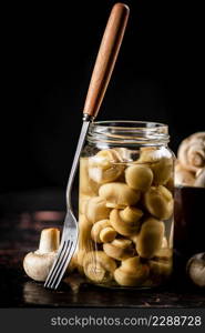 Open glass jar with pickled mushrooms. On a black background. High quality photo. Open glass jar with pickled mushrooms.