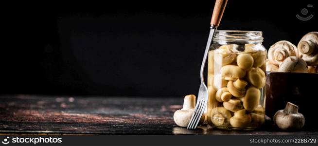 Open glass jar with pickled mushrooms. On a black background. High quality photo. Open glass jar with pickled mushrooms.