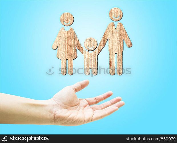 Open hand with wooden happy family icon on light blue background.