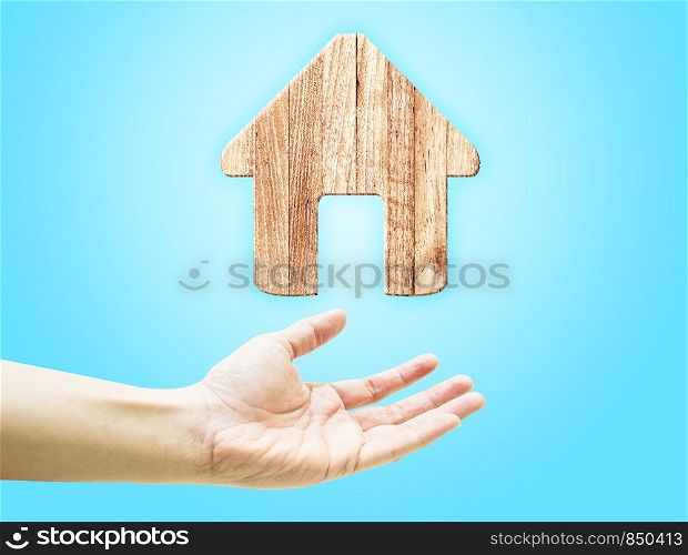 Open hand with wooden plank home icon on light blue background.