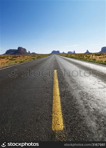 Open highway in scenic desert landscape with distant mountains and mesas.