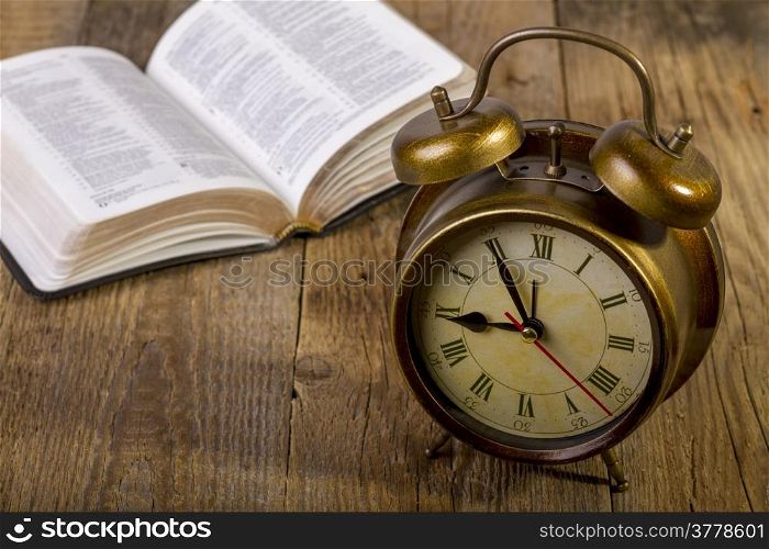 open Holy Bible with clock on wood