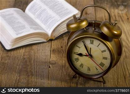 open Holy Bible with clock on wood