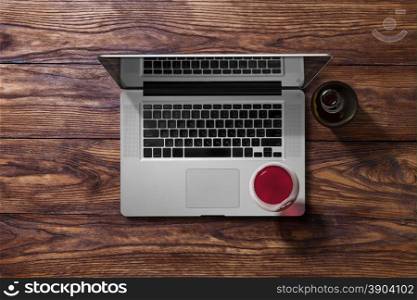 Open laptop and glass of wine. Open laptop and glass of red wine and bottle on brown wooden table. Top view