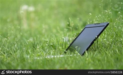 open laptop lying on green grass