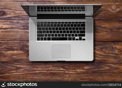 Open laptop on brown wooden table. Open laptop on brown wooden table. Top view