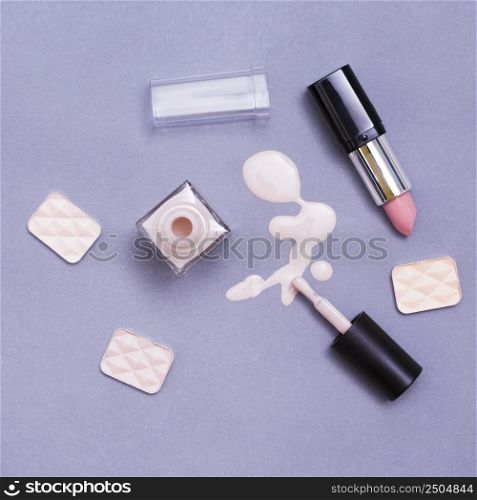 open lipstick nail varnish bottle eye shadows purple background