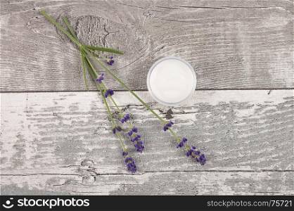 Open moisturizer and lavender on weathered wood