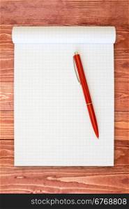 Open notebook and red pen on the wooden surface
