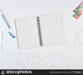 open notebook in a cell and on a white background, next to large blank puzzles, top view