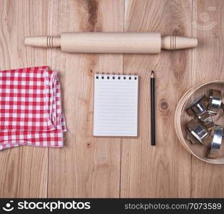 open notebook in a cell, round wooden sieve with baking molds, top view