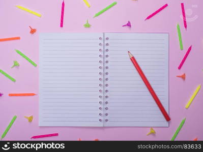 Open notebook in line and red wooden pencil on a pink background with wax festive candles