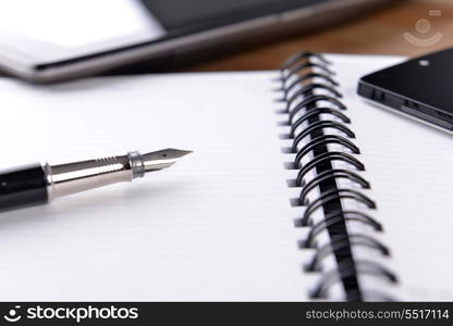 open notebook, mobile phone and black pen on white background