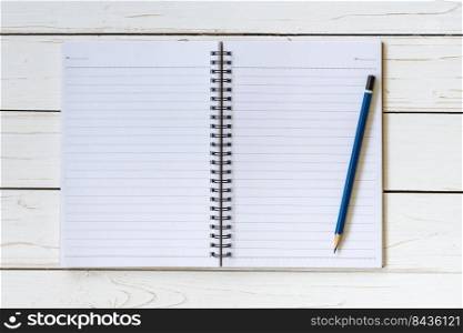 Open notebook with blank pages and pencil on wood table