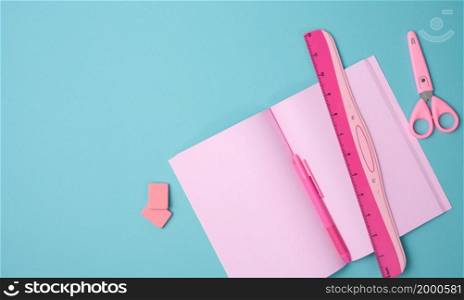open notebook with blank pink sheets, scissors and ruler on blue background, top view