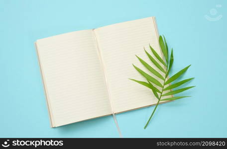 open notebook with blank white sheets on a blue background, top view.