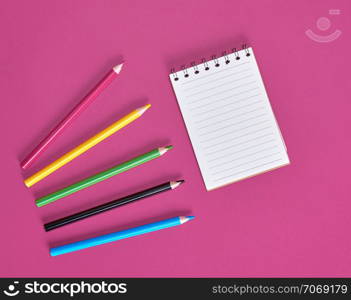 open notebook with empty white sheets and multicolored wooden pencils