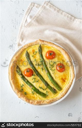 Open pie with asparagus and cherry tomatoes on the wooden table