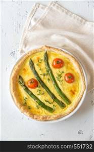 Open pie with asparagus and cherry tomatoes on the wooden table
