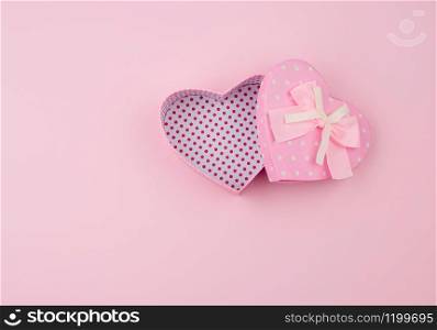 open pink gift box in the form of a heart with a bow on a pink background, top view, festive backdrop
