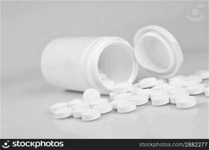 Open prescription bottles and white tablets scattered on table