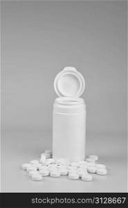 Open prescription bottles and white tablets scattered on table