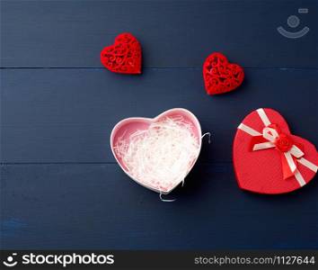 open red heart-shaped gift box with a bow on a blue wooden background, top view, festive backdrop