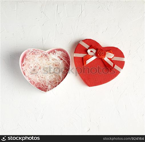 open red heart-shaped gift box with a bow on a white background, top view, festive backdrop