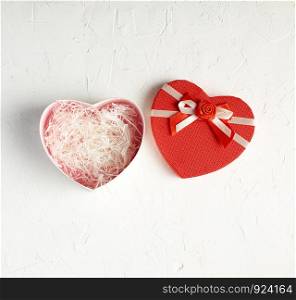 open red heart-shaped gift box with a bow on a white background, top view, festive backdrop