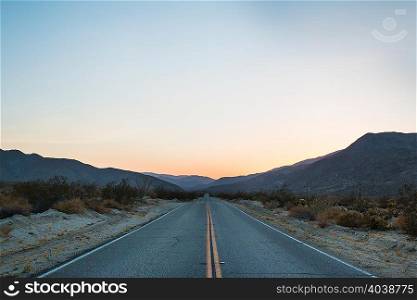 Open road to mountains at sunset, Anza Borrego, California, USA