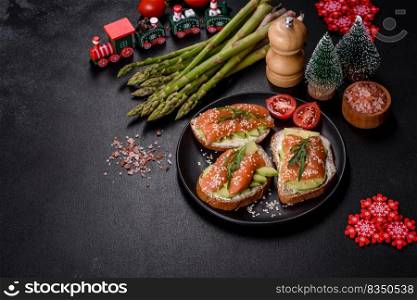 Open sandwich or toast. Grain bread with salmon, avocado and sesame seeds. Healthy snack, fat and omega 3 source on a christmas table. Toast sandwich with butter, avocado and salmon, decorated with arugula and sesame seeds, on a christmas table
