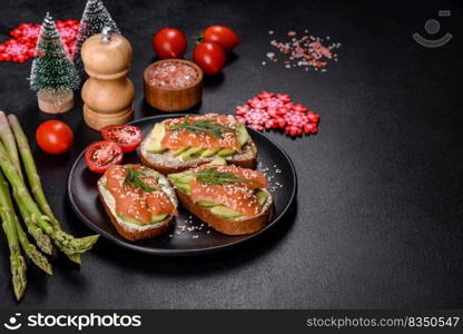 Open sandwich or toast. Grain bread with salmon, avocado and sesame seeds. Healthy snack, fat and omega 3 source on a christmas table. Toast sandwich with butter, avocado and salmon, decorated with arugula and sesame seeds, on a christmas table