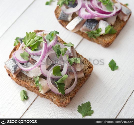 Open sandwich with herring, red onion and parsley