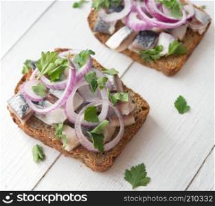 Open sandwich with herring, red onion and parsley