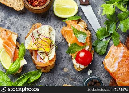 Open sandwich with salmon and vegetables.Small sandwiches.Toasts with salted salmon. Assorted bruschetta with fish