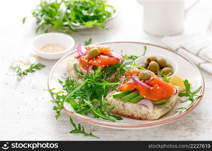 Open sandwiches with salted salmon, avocado, olives and arugula. Breakfast