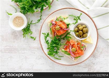 Open sandwiches with salted salmon, avocado, olives and arugula. Breakfast. Top view