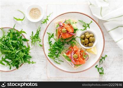 Open sandwiches with salted salmon, avocado, olives and arugula. Breakfast. Top view