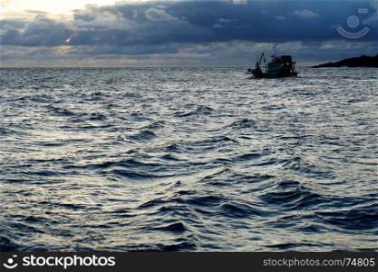 open sea in the evening with silhouette fishing boat