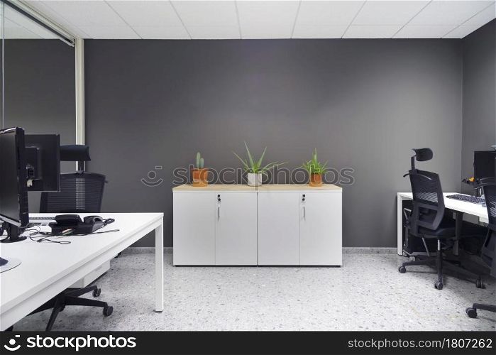 Open space office with computer monitors on white desks