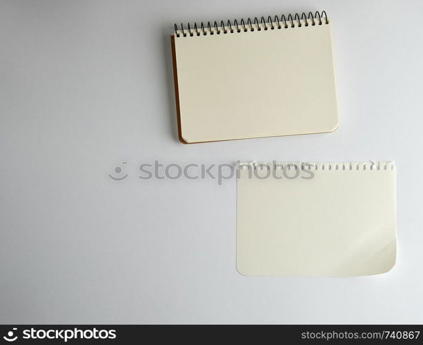open spiral notepad with empty white sheets on a white background, top view