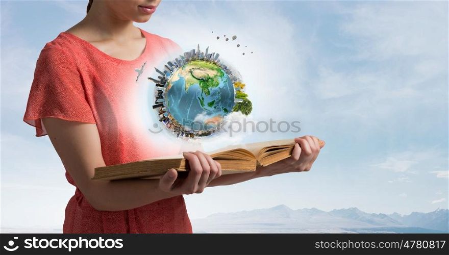 Open the whole world for yourself. Young woman in dress holding opened book. Elements of this image are furnished by NASA