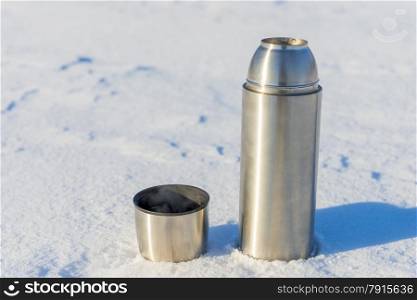 open thermos with boiling water in the snow in the winter