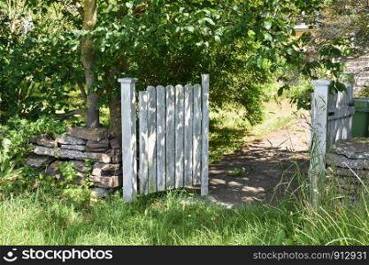Open white gate into a garden in summertime
