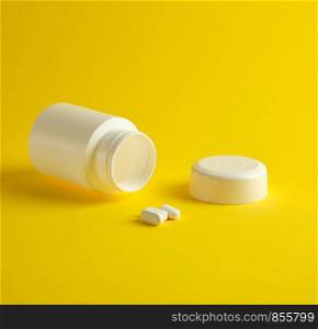 open white plastic jar for medicines and oval pills on a yellow background, blank for design and lettering