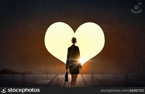 Open your heart. Rear view of businesswoman standing in light of doorway on the wall