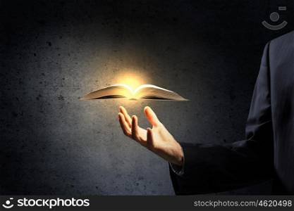 Opened book in hand. Hand of man holding old book on dark background