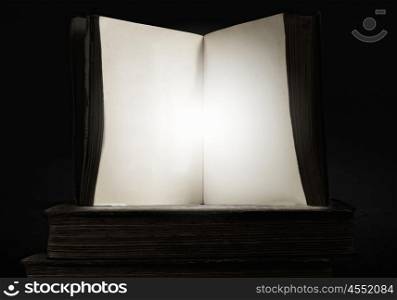 Opened book. Old opened book with light coming from pages on dark background.